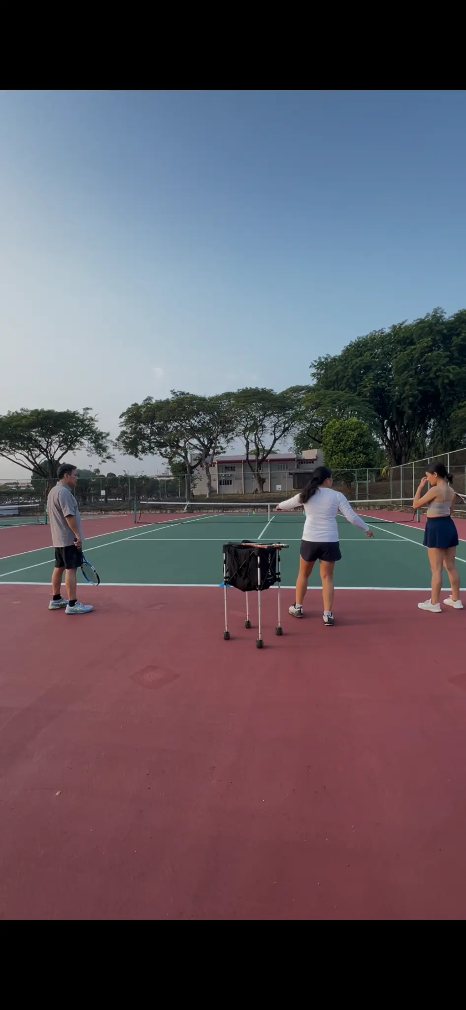 Coach Bei guiding a young tennis player on court